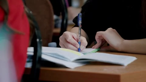 Close-up image of a student writing down information taught by the university Stock Footage 246882518
