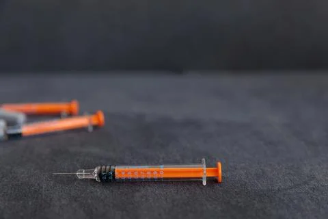 Close-Up Image of Syringes Featuring Bright Orange and Black Design Elements on Stock Photos