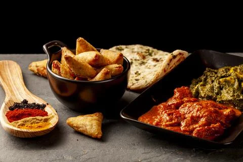 Close up image of a table with delicious dishes from India. Low light dark ba Stock Photos