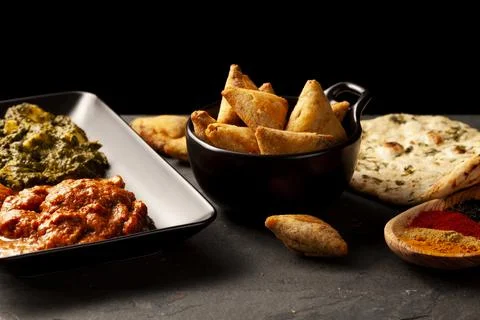 Close up image of a table with delicious dishes from India. Low light dark ba Stock Photos