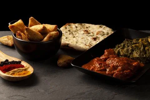 Close up image of a table with delicious dishes from India. Low light dark ba Stock Photos