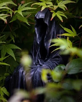 Close-up image of a tall, menacing statue depicting the Grim Reaper, wearing a b 写真素材
