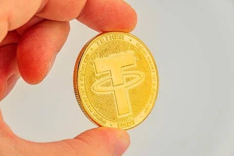 Close-up image of a Tether coin held by a hand, showcasing the B symbol and.. Stock Photos