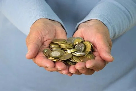 A close up image of two hands holding a pile of Euro coins Stock Photos