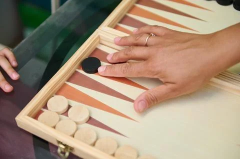 Close-up image of two hands playing backgammon on a wooden board, highlightin Stock Photos
