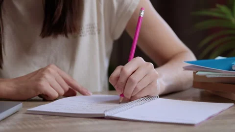 Close-up image of woman taking notes in notebook with simple pencil. Student Stock Footage 304931324