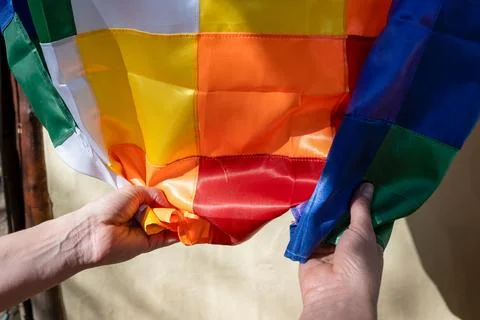 Close-up image of woman's hands clutching a silk Wiphala flag, a symbol com.. Stock Photos