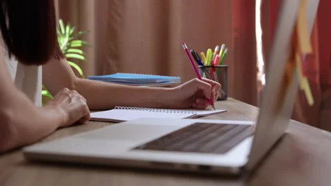 Close-up image of a young woman's hand taking notes in a notebook while Video stock 304933009
