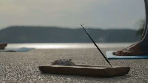 Close incense on background of people doing yoga at sunrise near the sea Stock Footage 102562650