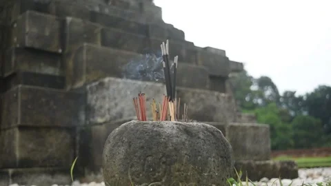 Close-up of incense glowing in a stone holder beside a temple Video stock 331839844
