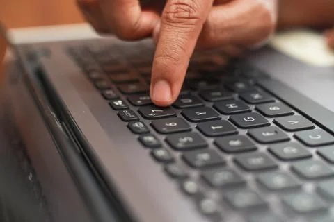 Close Up Of Index Finger Pressing Button On A Modern Gray Laptop Keyboard W.. Stock Photos