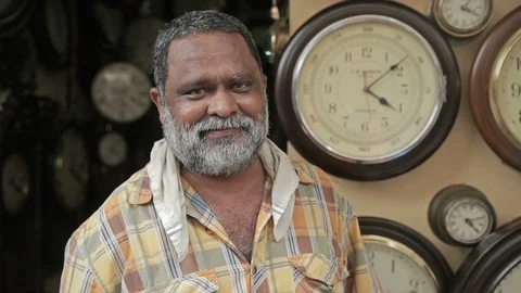 A close up of Indian antique wall clock shop owner standing in front his shop Stock Footage 85773765
