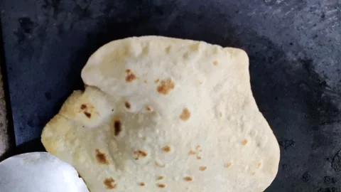A close-up of an Indian chef skillfully preparing fresh chapatis on a gas s.. Stock Footage 245324473