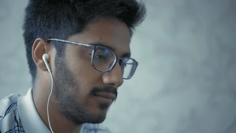 Close-up, Indian Guy with Glasses and Headphones Drinking Coffee and Looking at Stock Footage 111074704