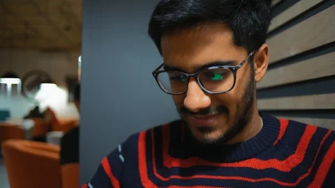 Close-up, Indian Guy Laughs Browsing the News Feed on a Smartphone Stock Footage 101660011