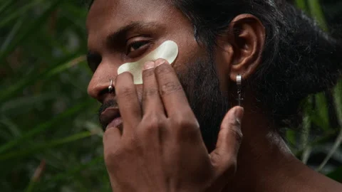 Close Up of Indian Man Applying Under Eye Patch in Jungle Forest Vídeos de archivo 310622415