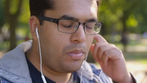 Close Up - Indian man bobs their head to music playing through earbuds while in Stock Footage 125093677