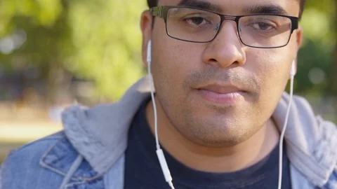 Close Up - Indian man dances around in the park to music coming from his earbuds Stock Footage 125094247