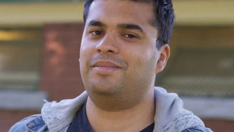 Close Up - Indian man looks into the camera and smiles - Slow Motion - shot on Stock Footage 125087781