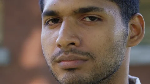Close Up - Indian man looks into the camera and smiles - Slow Motion - shot on Stock Footage 125089145