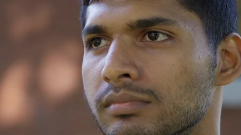 Close Up - Indian man looks off camera, serious and optimistic - Slow Motion - Stock Footage 125089498