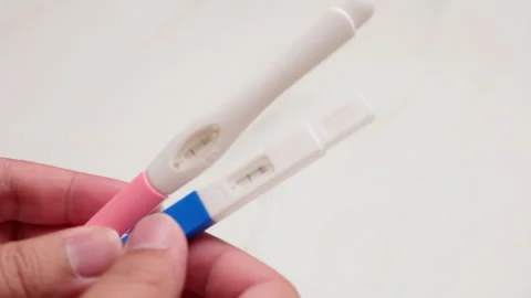 Close-up of an individual holding two kinds of home pregnancy test kits, Video stock 261165554