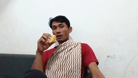 Close-up of an Indonesian man eating fried banana. Stock Footage 321941981