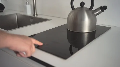 Close up induction cooktop, hand tapping, kettle on gas Stock Footage 110905485