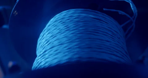 Close up of industrial cable spool with white wire under blue light Video stock 329500335