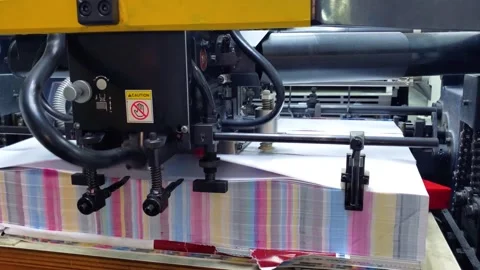 Close-up of industrial printing press machine feeding paper sheets through Stock Footage 338035477