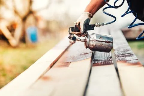 Close-up of industrial worker using paint gun or spray gun for applying paint Stock Photos
