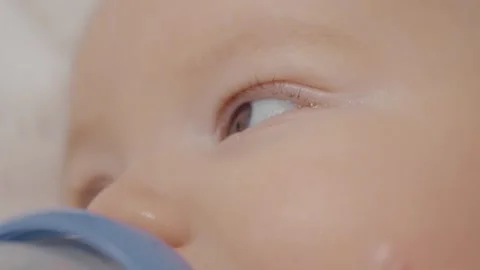 Close up infant eyes drinking formula milk while lying on bed. Stock Footage 302452706
