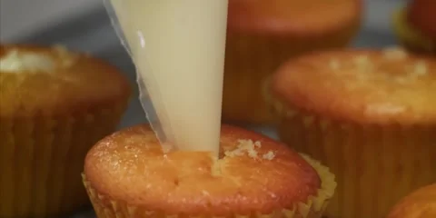 Close-Up of Injecting Sweet White Cream Filling Into Freshly Baked Cupcake Stock Footage 343588635