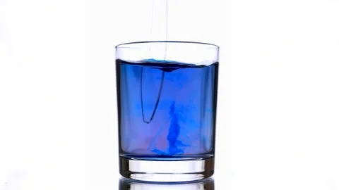 Close-up of an ink drops splashes into a glass of violet colored water. Stock Footage 152995068