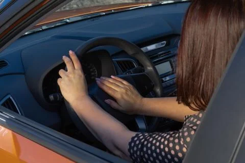Close-up inside car of hand pushing on steering wheel honking horn, female dr Stock Photos