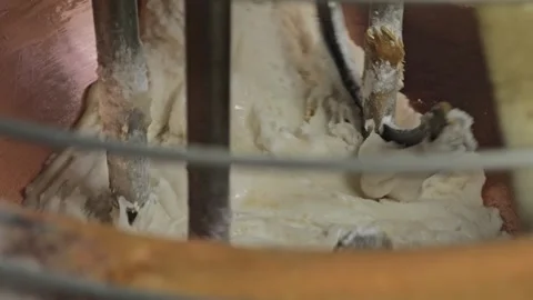 Close-up inside copper vat with creamy chocolate mixture swirling during Видео 327789585