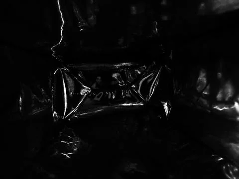Close up inside of empty black crumpled foil packaging with shiny silver re.. Фото
