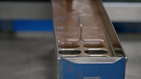 Close-up inside a popsicle factory showing chocolate popsicle mixture filling Stock Footage 337462361
