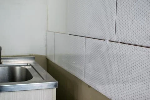Close-up of installed white ceramic tiles on walls of bathroom or kitchen. Ti Stock Photos