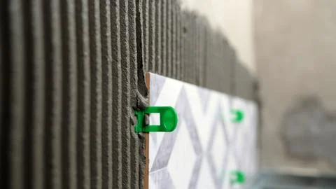 Close up of installing ceramic wall tiles using adhesive and green plastic .. Stock Photos