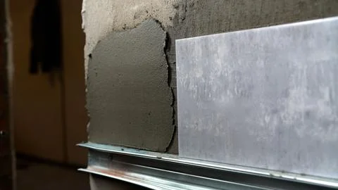 Close up of installing a grey ceramic tile on a wall with fresh mortar over.. Stock Photos