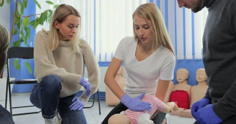 Close up instructor showing how to safe a life when the baby is choked sitting Stock Footage 163976726