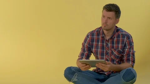 Close-up of Intelligent young man working on tablet on yellow background. Stock Footage 120463269
