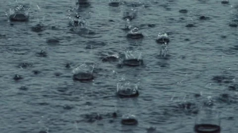 Close-up of intense raindrops hitting a wet surface and creating splashes. Stock Footage 340138215