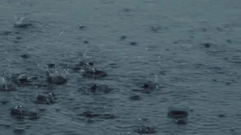 Close-up of intense raindrops hitting a wet surface and creating splashes Stock Footage 340581522