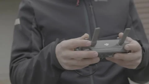 Close-up intense shaky orbit of a man holding a DJI Mavic remote controller Stock Footage 165393221