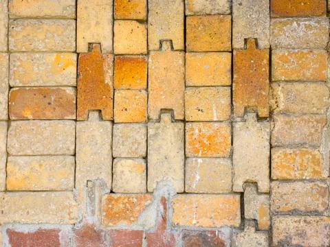 Close up of interlocking yellow and orange bricks in a textured wall 스톡 사진