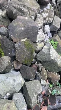 Close-up of irregular dark gray and brown rocks stacked together with green m Foto stock