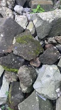A close up of irregular gray and brown rocks with patches of green moss and s Stock Photos