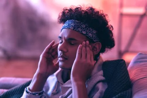 Close up of irritated guy trying to ease his sore head with his own hands Foto stock